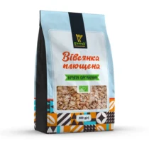 Bag of organic oats with a transparent window showing oats, light blue packaging and a colorful geometric pattern at the base, 300 g