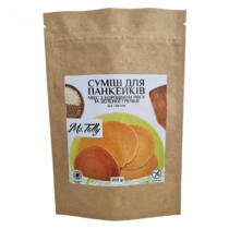 Brown kraft paper bag containing pancake mix, with a white label showing a stack of orange pancakes and grains on the side image.