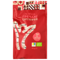 Red package for organic buckwheat crisps with decorative top pattern and Ukrainian text 'Хлібці гречані Organічні' and certification logos on the front